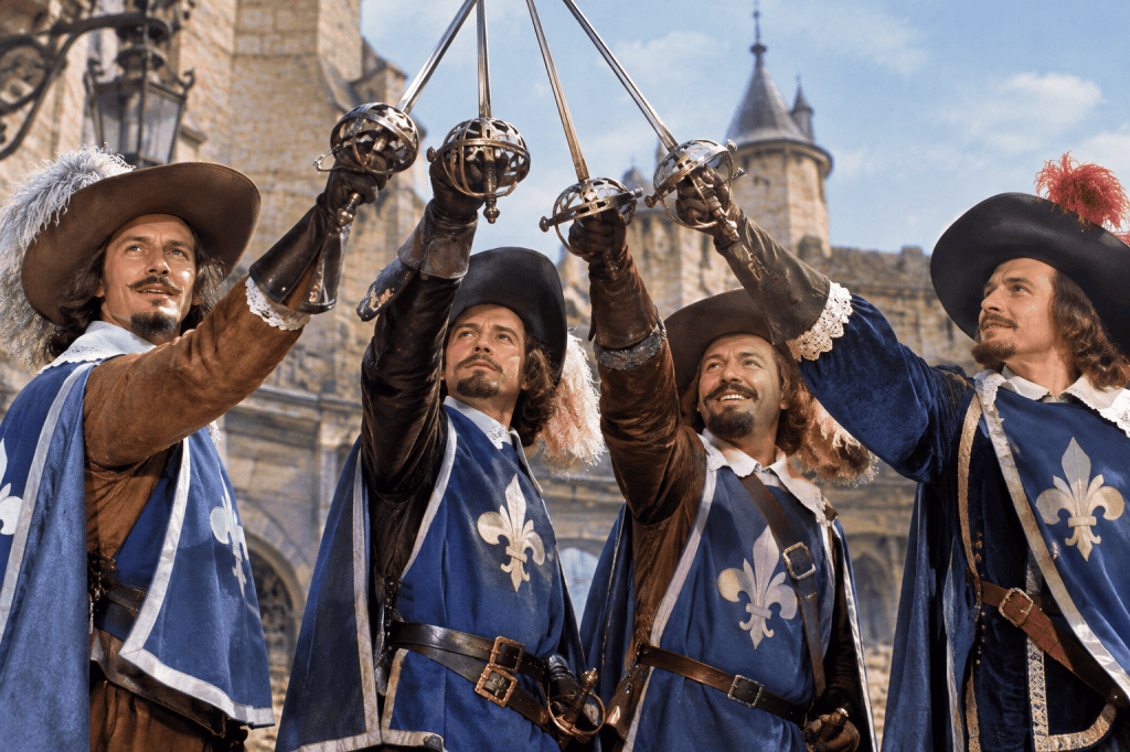 Four French musketeers raising their crossed swords in a historic courtyard
